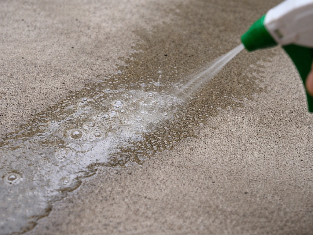 Close-up of acid etching on concrete with visible fizzing bubbles and wet darkened surface texture.