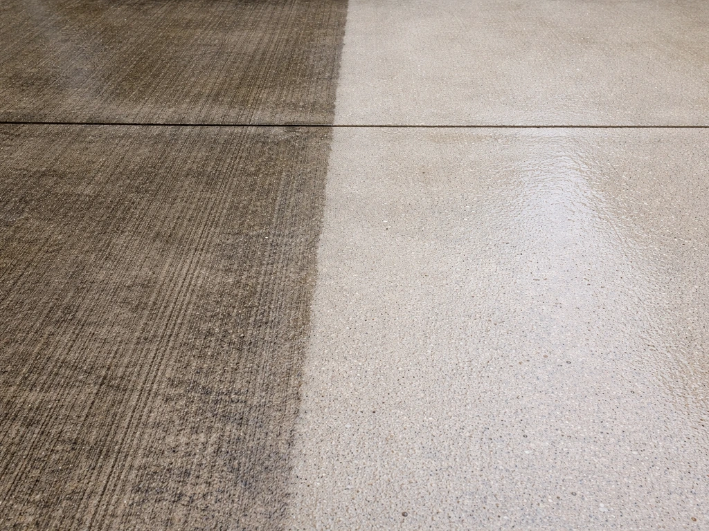 Close-up of a pressure-washed concrete patio showing cleaner concrete beside remaining grime.